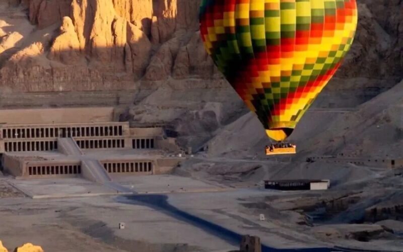 A hot air balloon drifting above the Theban necropolis near the Valley of the Kings