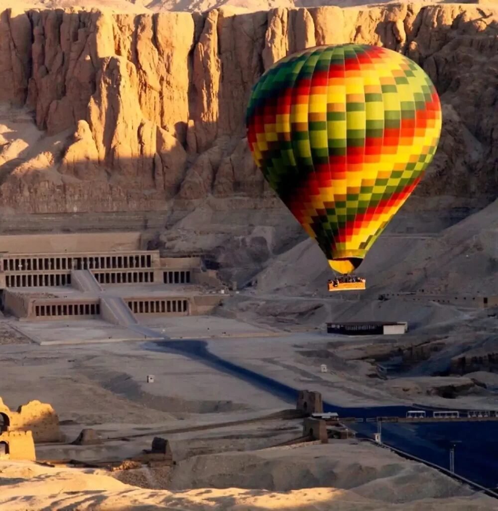 A hot air balloon drifting above the Theban necropolis near the Valley of the Kings