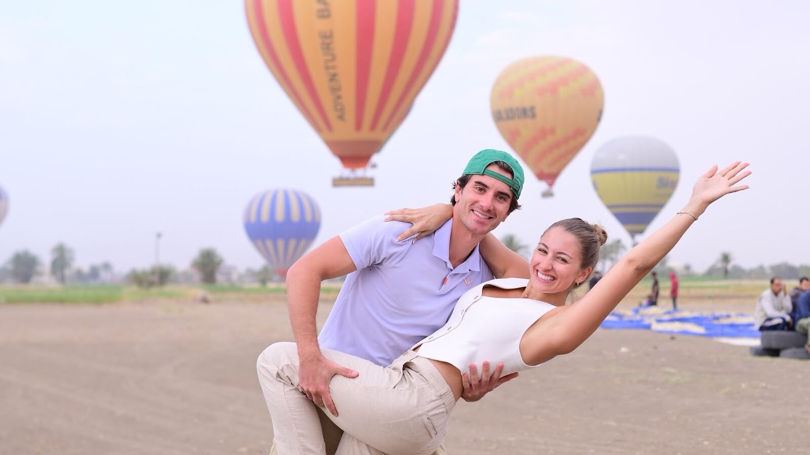 A couple photographed in front of a striped hot air balloon on the Luxor launch field