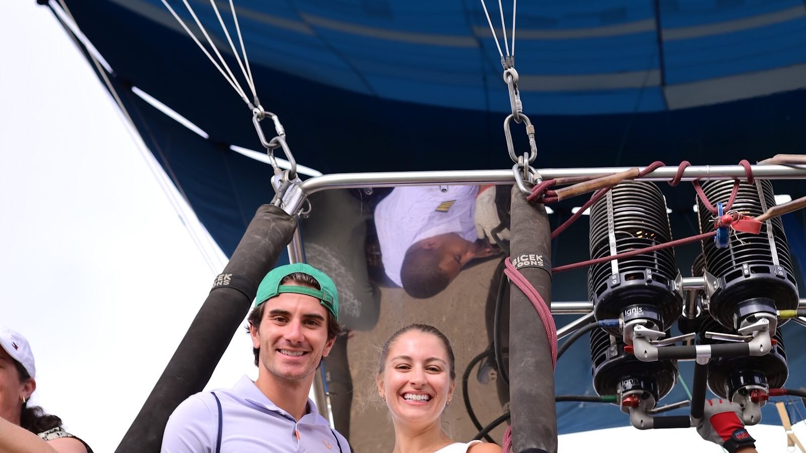 A group of passengers in a hot air balloon basket seen from below with the blue envelope overhead