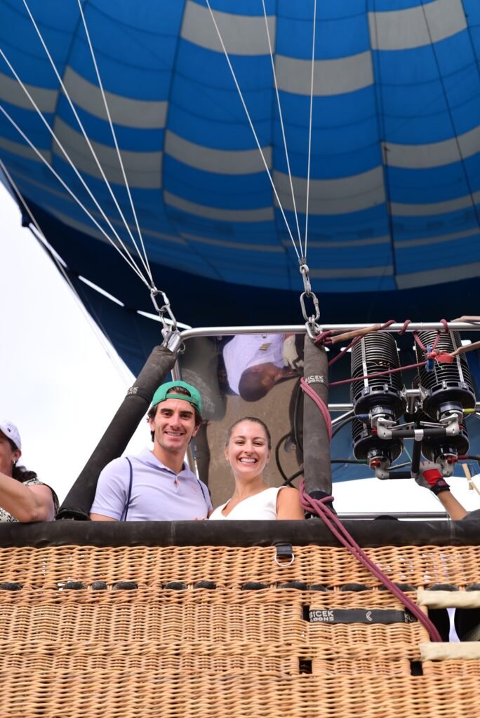 A group of passengers in a hot air balloon basket seen from below with the blue envelope overhead