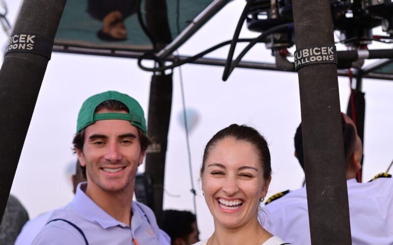 Two guests smiling in a hot air balloon basket on the Luxor launch field before take off