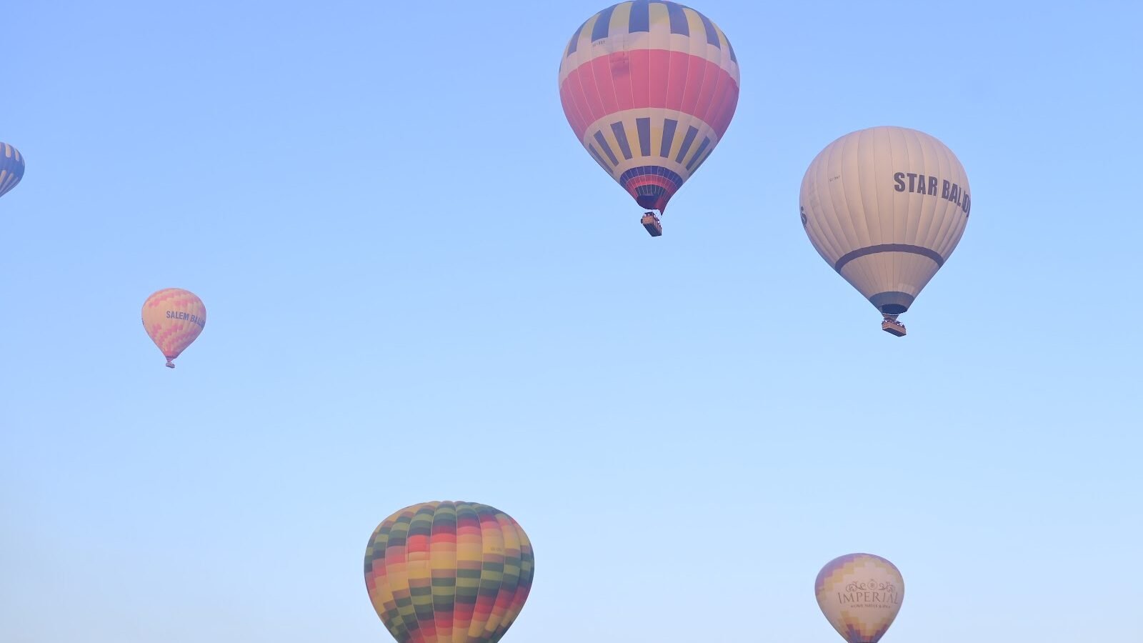 Two hot air balloons high in a clear blue sky above Luxor, Egypt