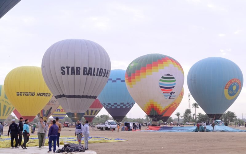 A row of hot air balloons being inflated side by side on the Luxor launch field at first light