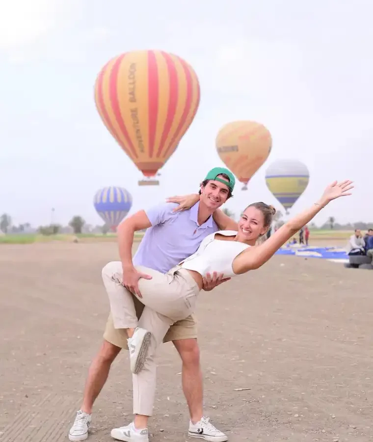 Couple in Egyptian-inspired costume photographed beside the Adventure Balloon envelope at sunrise on the Luxor West Bank