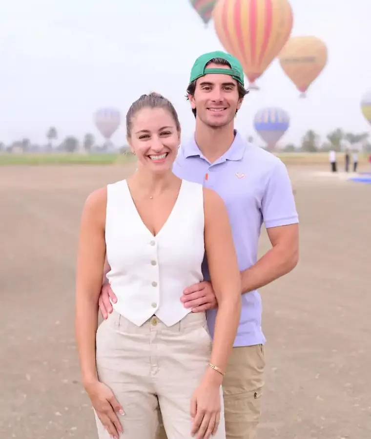Couple posing for their photo session with hot air balloons inflating behind them in Luxor