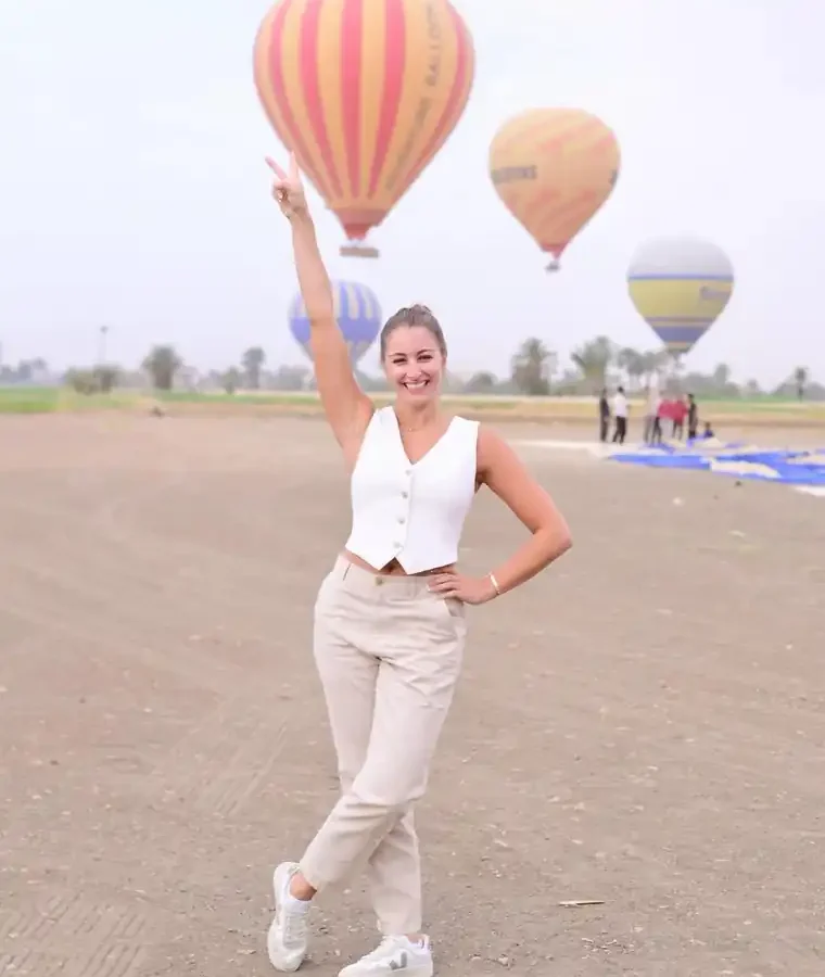 Guest in a white vest and beige trousers with arm raised during a Luxor balloon photo session