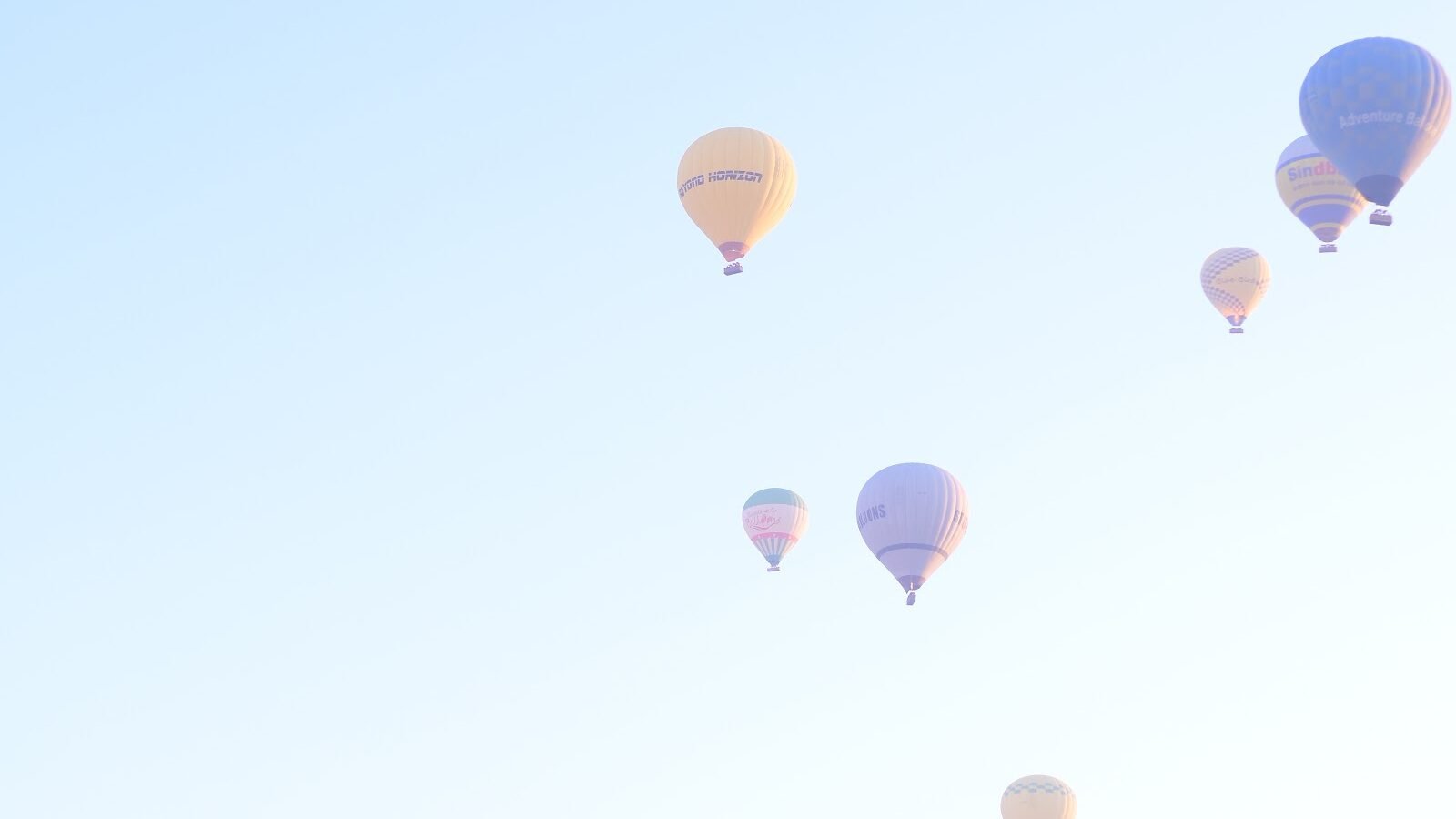 Dozens of distant hot air balloons seen from the air during a sunrise flight over Luxor