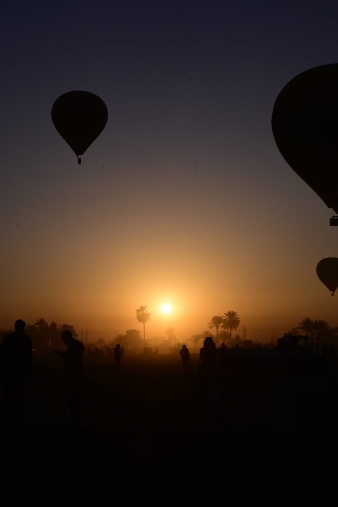 The sun rising through haze over Luxor's West Bank with a balloon silhouetted alongside